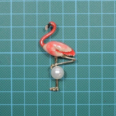 Broche flamingo cor-de-rosa com pérola branca sobre fundo quadriculado azul
