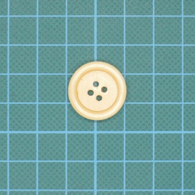 Botão plástico bege com quatro furos sobre fundo quadriculado verde azul