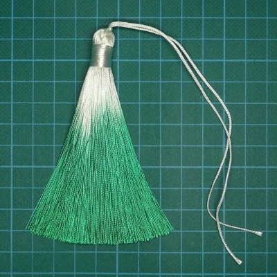 Pente de seda branco a verde com cordão sobre superfície quadriculada verde