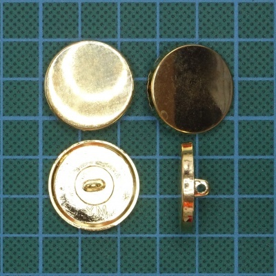 Conjunto de botões metálicos dourados lisos sobre superfície de corte verde com grade azul