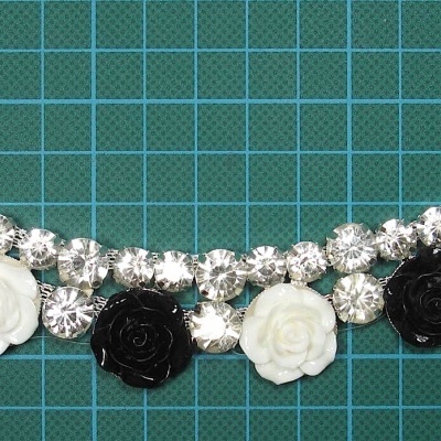 Colar com pedras brilhantes e flores preto e branco sobre fundo quadriculado verde