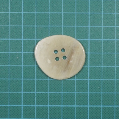 Botão redondo nacarado bege com quatro buracos em grelha verde