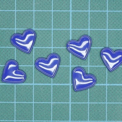 Seis corações azuis com contorno branco sobre superfície verde quadriculada