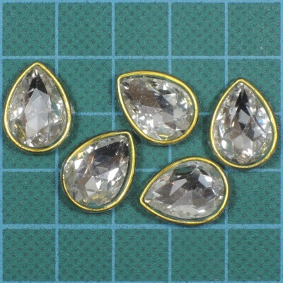 Cinco pedras decorativas em formato de gota com borda dourada sobre fundo quadriculado azul e verde