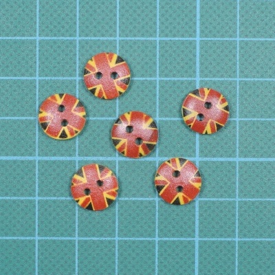 Seis botões redondos com padrão vermelho, preto e amarelo sobre base verde quadriculada.