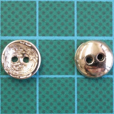 Dois botões metálicos redondos com dois furos em superfície de grelha azul e verde