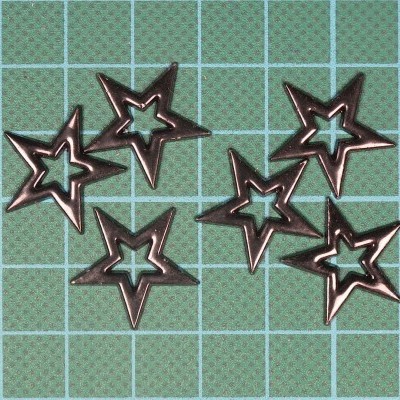 Seis estrelas decorativas metálicas prateadas sobre fundo verde com grelha