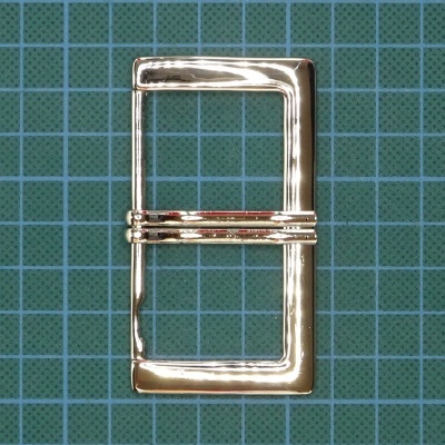 Fivela metálica retangular dourada sobre fundo azul com padrão de grelha