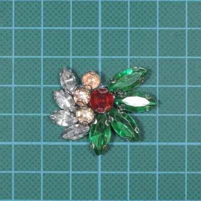 Broche colorido com pedras sobre papel quadriculado verde