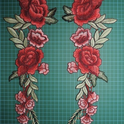 Apliques bordados de flores vermelhas e rosas com folhas verdes sobre fundo quadriculado verde.