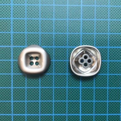Dois botões quadrados cinza metálico em superfície azul com grelha