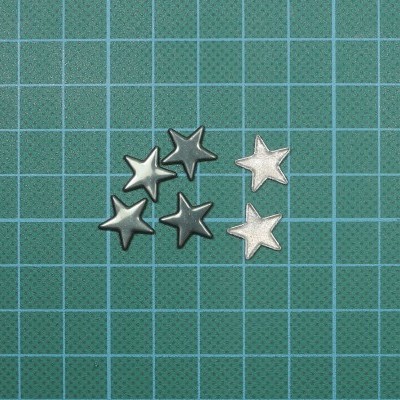 Estrelas decorativas em metal prateado e cinza sobre fundo verde quadriculado