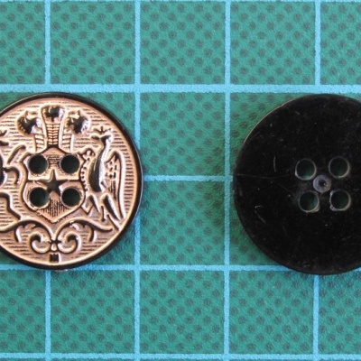 Dois botões redondos, um dourado com padrão decorativo e outro preto liso, sobre fundo azul quadrado.