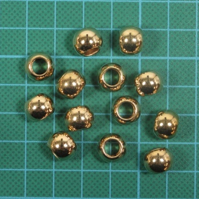 Conjunto de contas metálicas douradas redondas sobre tapete de corte verde