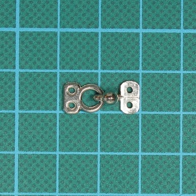 Fecho metálico prateado sobre superfície verde com grelha azul