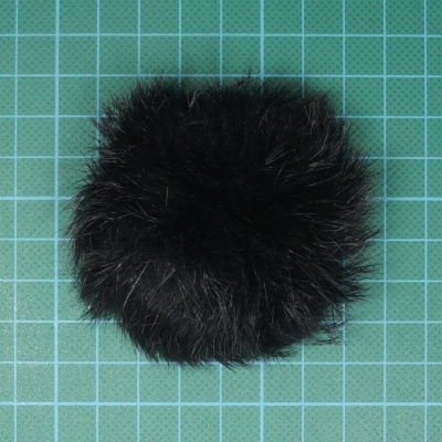 Pom pom preto felpudo num tapete de corte verde