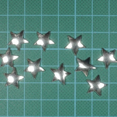 Estrelas metálicas prateadas sobre superfície verde com grelha