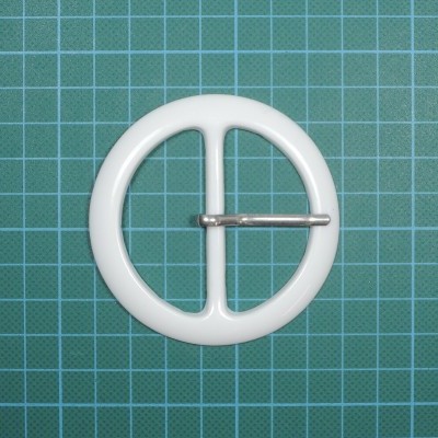 Fivela redonda branca com pino metálico sobre superfície quadriculada azul