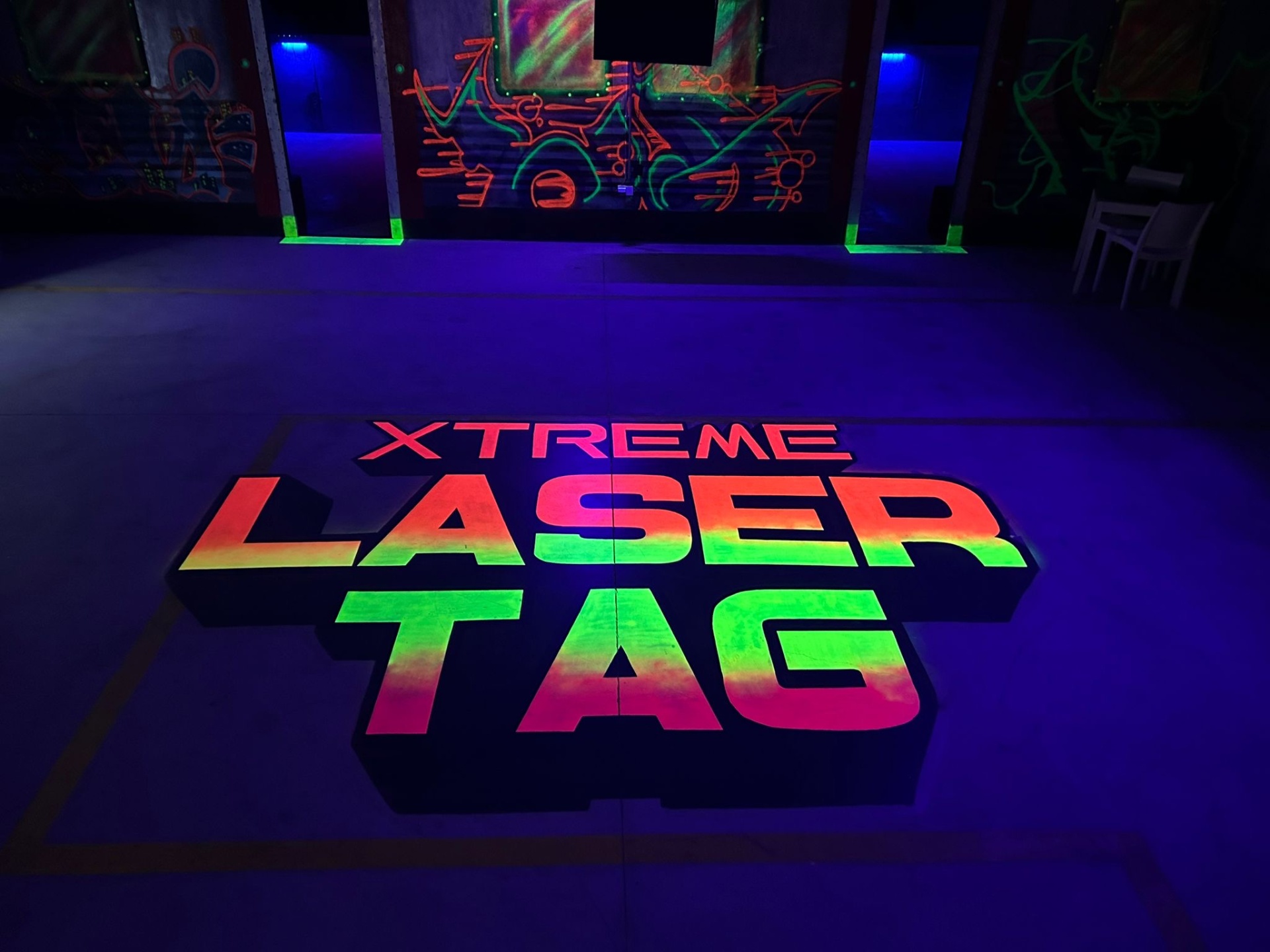 Gift Voucher - Xtreme Laser Tag, Sintra | 5 pessoas Piso escuro com texto colorido 'XTREME LASER TAG' e grafites neon ao fundo.