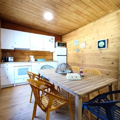 Cozinha de madeira com móveis brancos e cadeiras amarelas e azuis