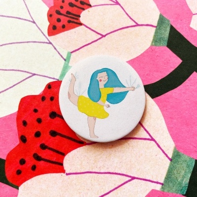 Botão redondo branco com ilustração de mulher dançando com cabelo azul e vestido amarelo