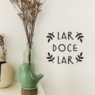 Conjunto decorativo com vasos, figura de pássaro cerâmico verde e texto na parede