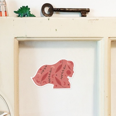 Adesivo rosa de lobo com desenhos florais numa porta branca com chave e figuras decorativas