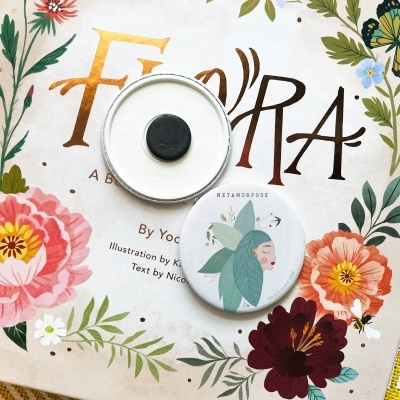 Dois espelhos redondos com imagem de fada, sobre capa de livro floral em pano amarelo