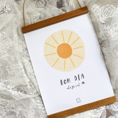 Quadro decorativo pendurado com ilustração de sol amarelo e texto 