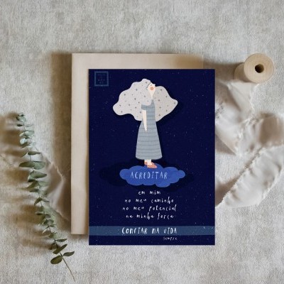 Cartão postal azul com ilustração e texto motivacional, envelope bege, fita branca e ramo de folhas secas numa superfície cinza