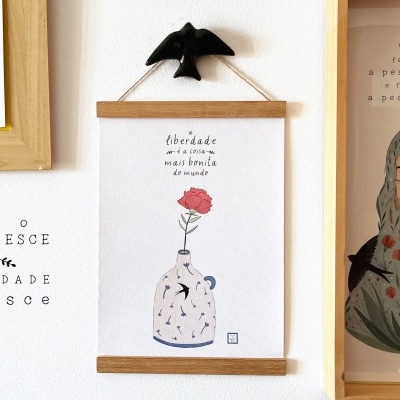 Três quadros decorativos com textos e ilustrações na parede branca com um pássaro negro decorativo