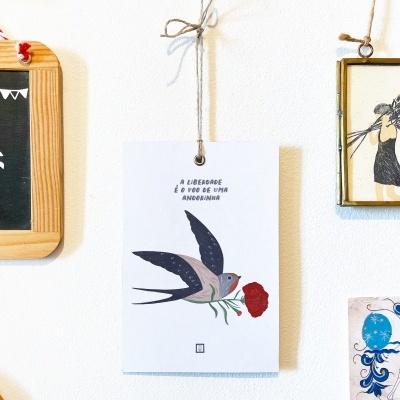 Quadros decorativos pendurados numa parede branca com desenhos e texto em português.