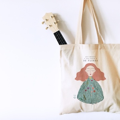 Saco de tecido cru com ilustração colorida e texto, com violão meio visível dentro