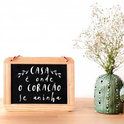 Placa decorativa com texto e vaso em forma de cacto com flores