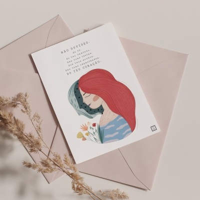 Cartão ilustrado com mulher e texto inspirador sobre envelope rosa e planta seca