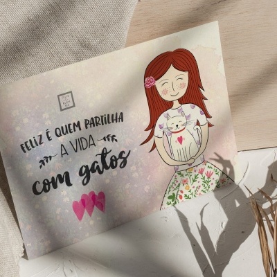 Postal ilustrado com texto e desenho de mulher com gato sobre tecido bege