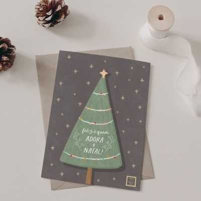 Cartão de Natal com árvore desenhada, envelope bege, pinhões e fita branca