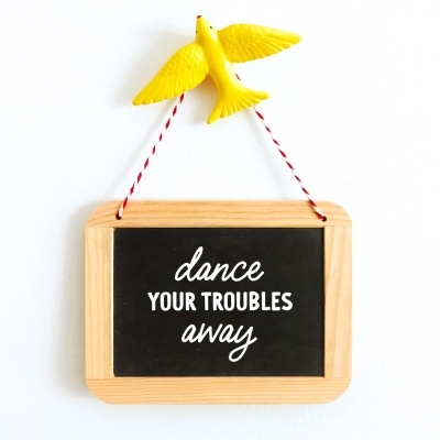 Placa decorativa com texto em fundo preto e pássaro amarelo para pendurar