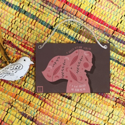 Objeto decorativo com silhueta feminina e texto sobre tapete colorido.