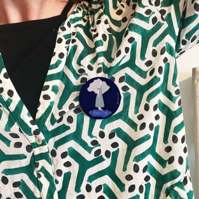 Broche azul com árvore branca em roupa com padrão geométrico verde e branco