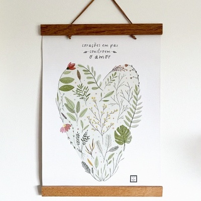 Cartaz branco com ilustração de coração feito de folhas e flores pendurado numa parede branca