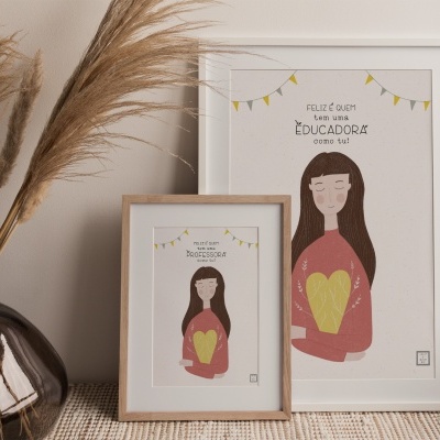 Dois quadros com ilustração de mulher e texto, sobre uma superfície ao lado de um vaso com plantas secas.