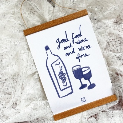 Póster com desenho de garrafa de vinho e taças, texto em inglês, moldura de madeira clara, sobre tecido rendado branco