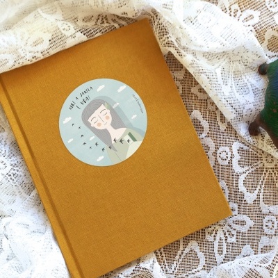 caderno mostarda com ilustração e texto BY THE POOLS ao lado de figura de dinossauro