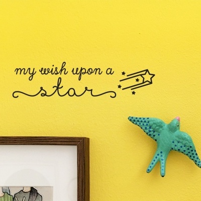 Parede amarela com autocolante preto 'my wish upon a star' e pássaro decorativo azul