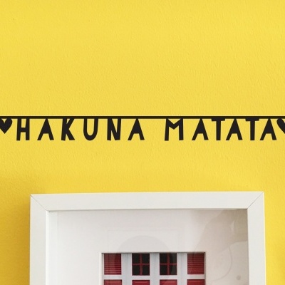 Vinil decorativo preto com texto HAKUNA MATATA numa parede amarela