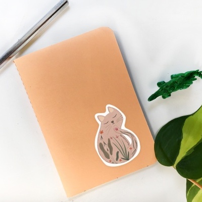 Caderno com autocolante de gato, caneta e planta