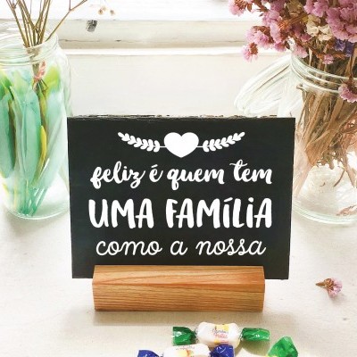 Placa decorativa preta com texto branco numa mesa branca com vasos de vidro e doces coloridos
