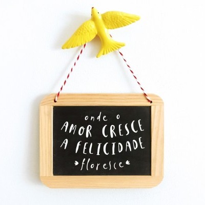 Quadro pequeno em madeira com texto em branco em fundo preto e pássaro amarelo