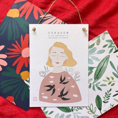 Três postais decorativos com uma ilustração e padrões florais sobre tecido vermelho.